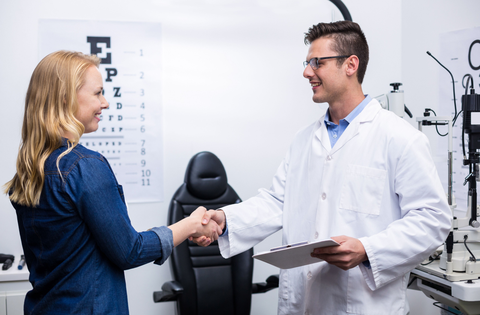 A woman in an optometry clinic shaking hands with a male optometrist.
