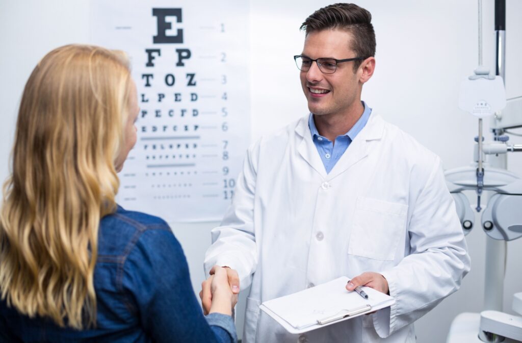 A woman in an optometrist's office shaking hands with her optometrist.