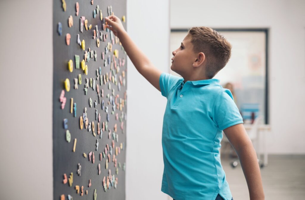 A child works on visual discrimination based on letters and numbers on a blackboard.