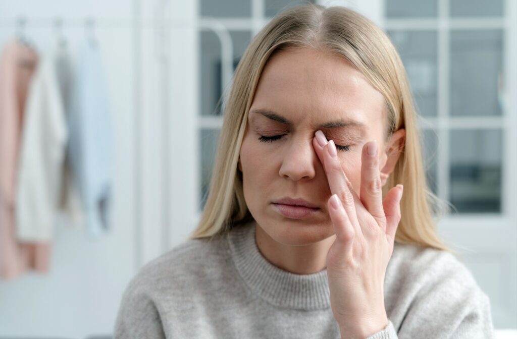 Blonde woman rubbing her left eye.