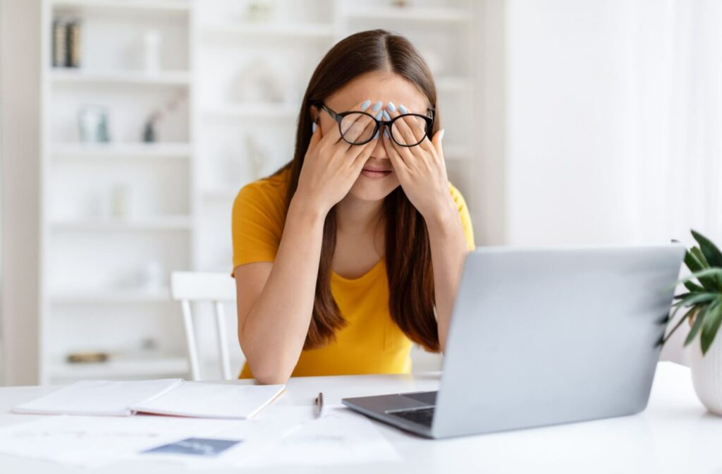 A woman rubs her tired eyes from spending a long time working on her laptop.