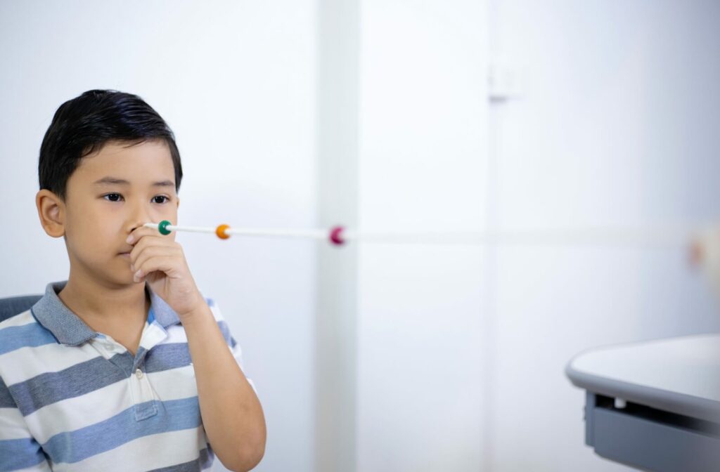 A child with strabismus focuses on a string with beads during vision therapy.