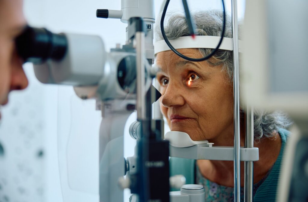 A senior looks into a machine used by an optometrist to have their eyes checked for signs of Graves’ eye disease.