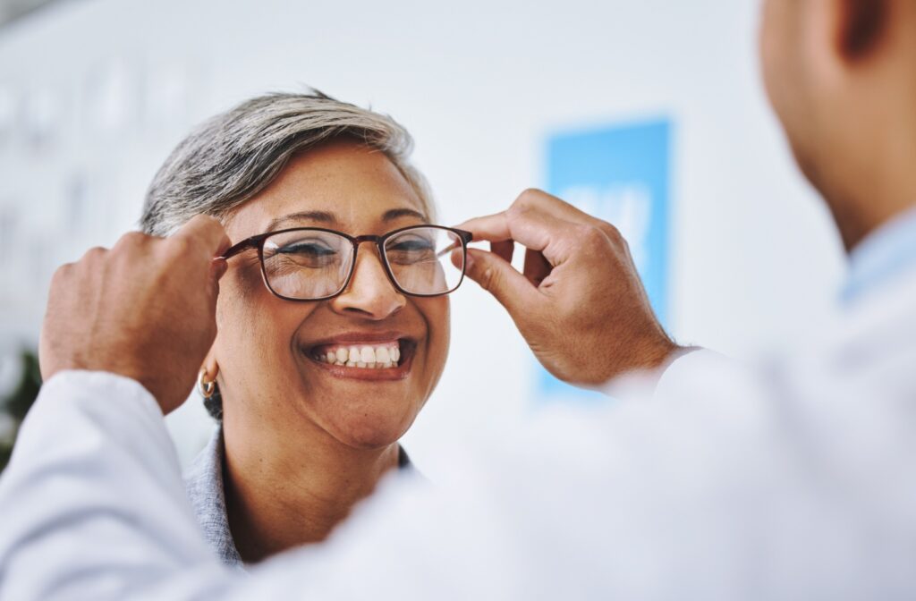 Person smiling while optometrist puts new computer glasses on them.